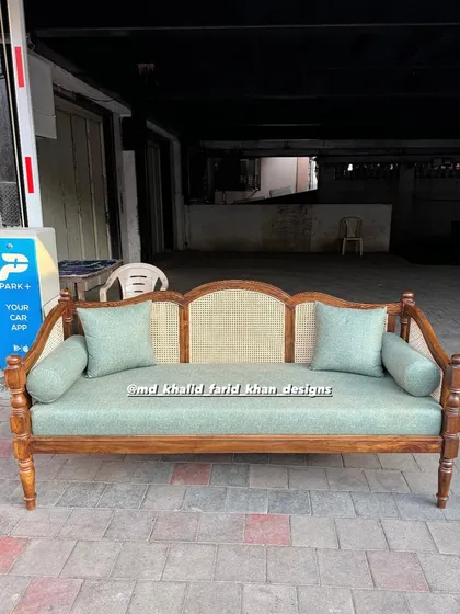 Front view of the handcrafted daybed, showcasing the bolster pillows and detailed woodwork.