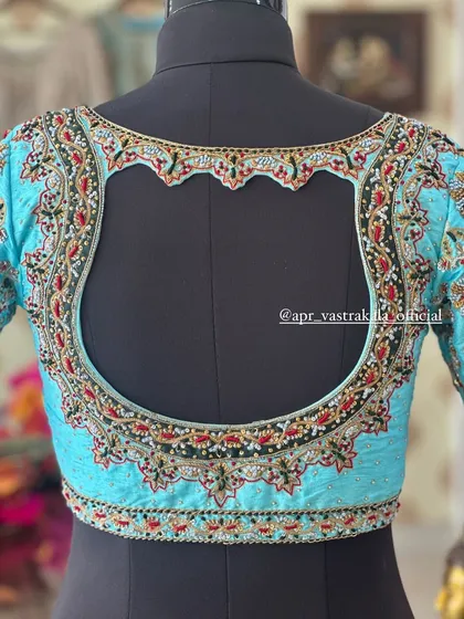 Showcasing an intricate back design on a mannequin. This light blue blouse features a scalloped cutout framed with dense floral embroidery, demonstrating my commitment to detailed craftsmanship on every part of the garment.