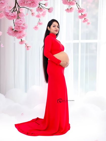 A beautiful side profile in a red cutout gown, set against a dreamy backdrop of clouds and cherry blossoms.