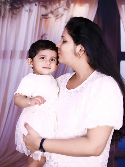 A beautiful portrait of a mother holding and kissing her daughter's forehead.