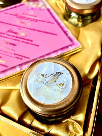 A close-up of a personalized jar lid, showing the couple's initials in elegant gold calligraphy. This small detail adds a significant touch of personalization to the hamper, making your guests feel truly special.