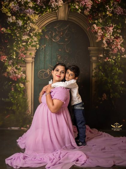 A loving hug from a son who can't wait to meet his new sibling. This studio portrait showcases the warmth and affection of this growing family against one of our elegant, hand-painted backdrops.