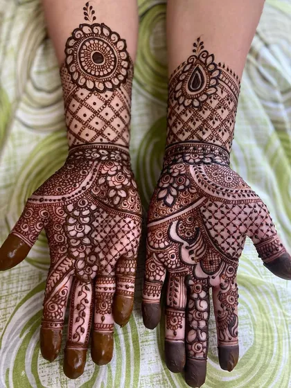 This design showcases a mix of styles, with intricate floral and paisley work on the palm and a bold grid pattern on the back of the hand.