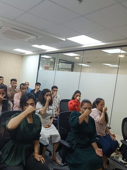 An instructor demonstrates alternate nostril breathing (Nadi Shodhana) to a group of employees. This pranayama is highly effective for balancing the nervous system and improving concentration during a busy workday.