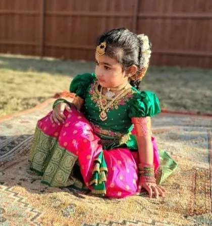 This little girl looks like royalty in her custom silk Pattu Pavadai. The rich green blouse with puffed sleeves and the vibrant pink skirt with a traditional gold border is a classic combination that I adore making.