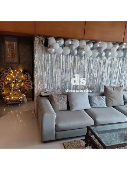 For this 25th anniversary celebration at home, we created a simple yet elegant backdrop in the living room using a silver foil curtain and a silver balloon garland.