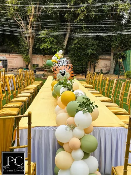The safari theme extends to the guest tables with a long, flowing balloon runner. This table centerpiece incorporates animal-shaped balloons and matching colors, making the entire party space feel cohesive and fun.