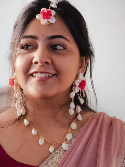 A close up candid shot of the bride during her Haldi ceremony. Her natural smile and the beautiful floral jewelry are the focus of this happy bridal portrait.