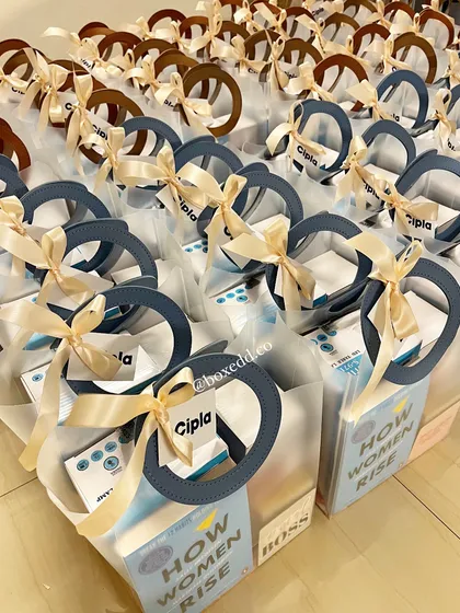 The final, beautifully assembled Women's Day gift bags for Cipla, tied with a satin ribbon and a branded tag.