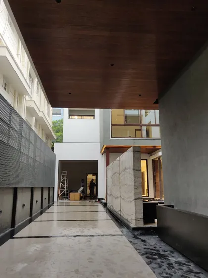 The same residential project nearing completion. Here, the finished marble flooring, wood-paneled ceiling, and stone feature wall are installed, showcasing the "after" state and the quality of the material finishes.