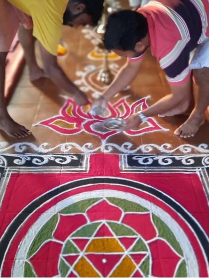 Two students work together to complete the rangoli design. Karma yoga, or selfless service, is a key pillar of our ashram life.