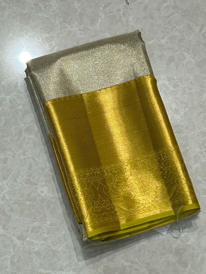 A shimmering gold tissue Kanchi silk saree with a bright yellow border.