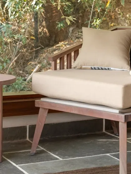 A quiet moment in the mountain home. The simple wooden armchair and side table create an understated and peaceful spot to relax, surrounded by the beauty of nature.