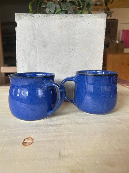 A collection of my handmade ceramic mugs, each with its own unique shape and glaze. The little coffee bean detail on the handle is a fun touch for coffee lovers.