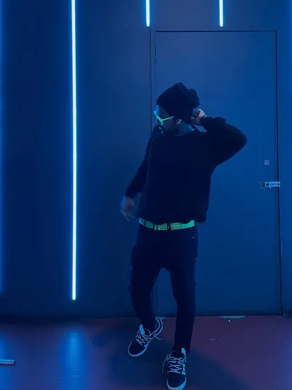 A dynamic pose against a wall of blue light, capturing the energy and movement of my performance.
