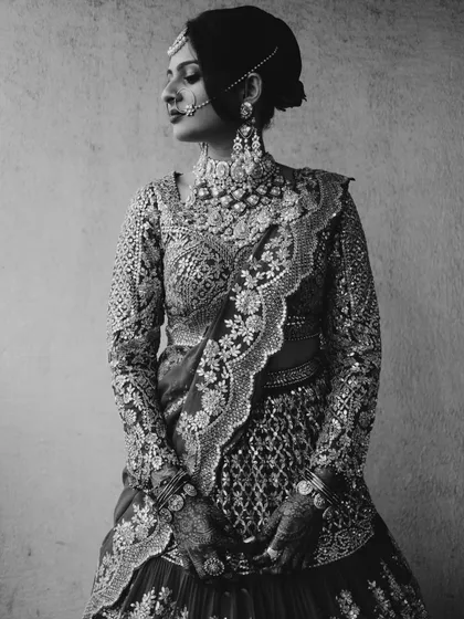 This black and white portrait emphasizes the incredible craftsmanship of the bridal lehenga. The full-sleeved blouse with dense embroidery and the elegant drape of the dupatta create a timeless and sophisticated look.
