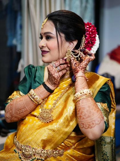 A "getting ready" shot from the baby shower. The mom-to-be is all smiles as she puts on her traditional temple jewelry.