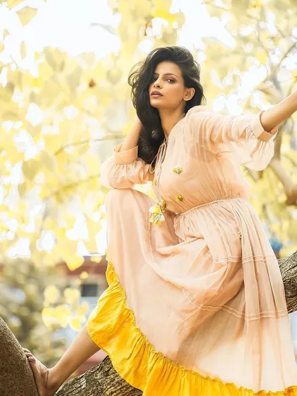 A whimsical fashion portrait. The hair is styled with volume and soft texture to create a romantic, dreamy look that complements the outdoor setting.