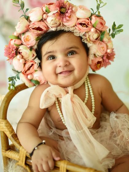 A close-up on this little doll's happy face. The oversized floral bonnet and pearl necklace add a touch of vintage charm to this six-month milestone photoshoot.