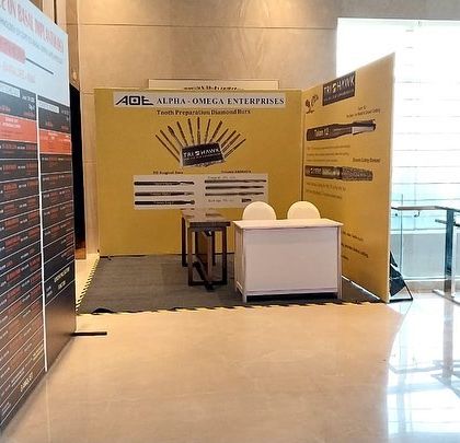 A wider view of the Alpha Omega Enterprises trade show stall, showing how it fits within the larger exhibition hall. My designs consider traffic flow and visibility to maximize impact.