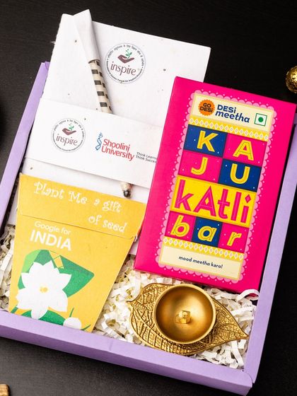 An eco-friendly and thoughtful gift, this hamper includes a plantable seed paper note from Google for India, a Kaju Katli bar, and a beautiful brass leaf diya. It's a sustainable way to celebrate the festival of lights.