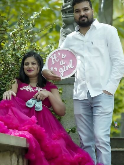 A sweet gender reveal photo for a baby girl. The couple uses both a sign and a tiny pair of baby shoes to share their news in this lovely garden setting.