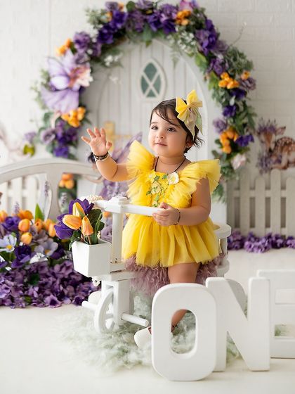 A happy wave from the birthday girl in her yellow and purple fairy house setup.