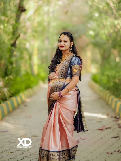 A classic portrait of the mother-to-be in a silk saree, posing elegantly on a tree-lined path.