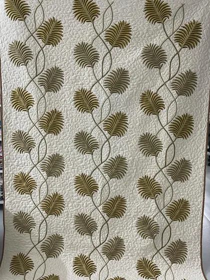 A beautiful quilt featuring delicate leaf appliqué.
