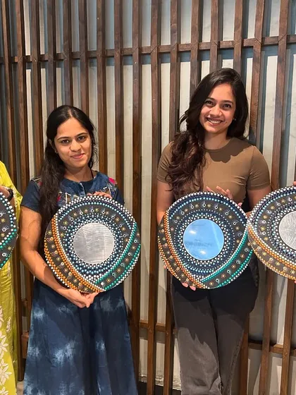 Four happy artists showing off their unique spiral mirror mandalas, each with a different color combination.