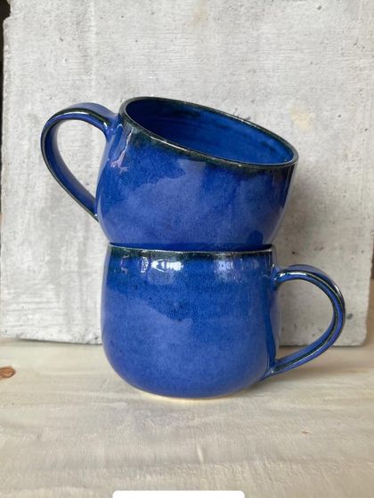 A collection of my handmade ceramic mugs, each with its own unique shape and glaze. The little coffee bean detail on the handle is a fun touch for coffee lovers.