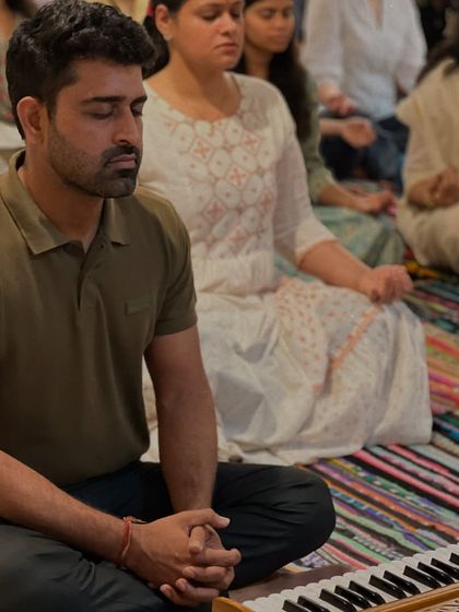 A participant finds a moment of deep inner quiet during our anniversary satsang. The harmonium in the foreground suggests the role of kirtan and devotional music in our practice.
