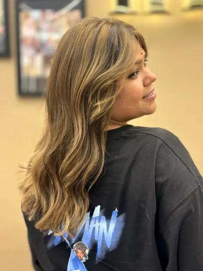 A side profile showcasing soft, sun-kissed highlights. The color adds dimension and movement to her medium-length hair.