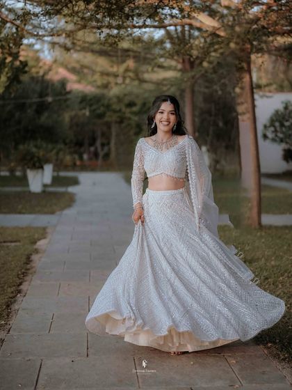 A joyful, twirling shot of the bride in her white reception lehenga, full of movement and happiness.