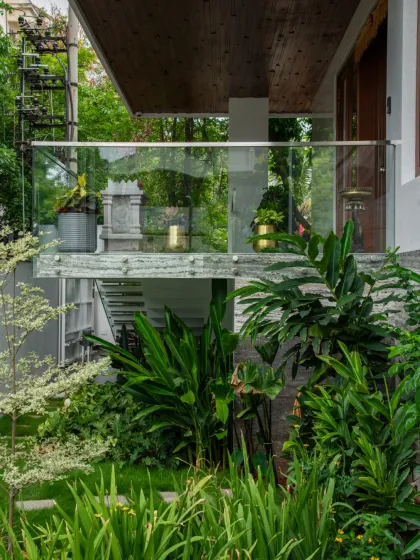 This design showcases a perfect blend of architecture and landscape. A glass-railed balcony overlooks a densely planted garden, creating a harmony between the clean lines of the home and the organic forms of nature.