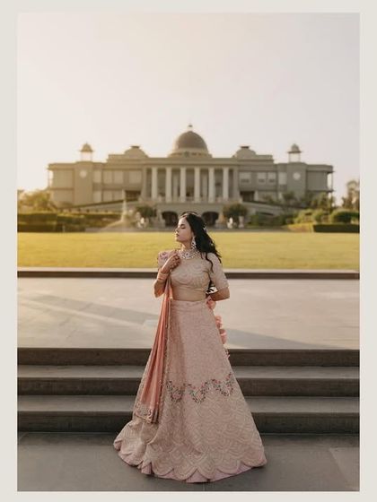 A beautiful portrait of Divya at her Mehendi ceremony, with the grand facade of Raffles Udaipur in the background. Her soft pink lehenga and serene expression create a picture of pure elegance.
