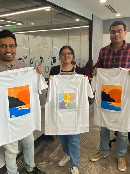The finished masterpieces! A group of proud artists holding up their sunset-themed painted shirts. This is what a fun and productive team building event looks like.