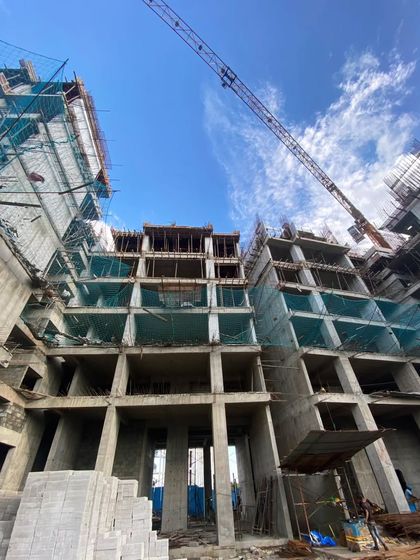A low-angle shot of a tower under construction in Bhayander. The image emphasizes the verticality of the structure and the intricate network of scaffolding and formwork required to build it.