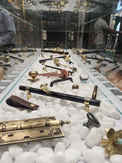 A display case from our exhibition booth, showcasing a variety of our smaller hardware pieces, such as cabinet knobs and hinges, like jewels on a bed of white stone.