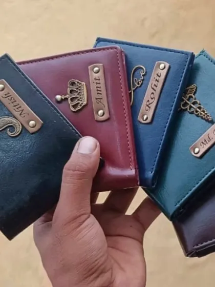 You can choose from a wide range of colors and charms to create the perfect wallet. This image shows a variety of my personalized wallets in black, maroon, blue, green, and purple, each with a unique charm like a crown, infinity symbol, or caduceus for a doctor.