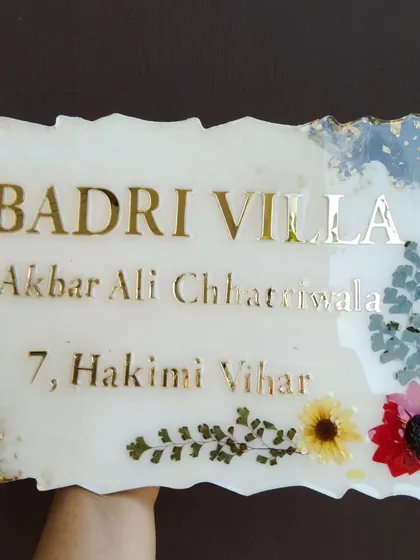 Make your front door stand out with a custom resin nameplate. For this 'Badri Villa' sign, I used a white marble effect, gold lettering, and embedded real dried flowers to match the family's style.