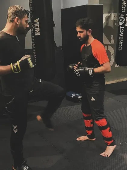 An instructor holds pads for a student, guiding him through a kicking combination. This is a fundamental part of our training, building power, accuracy, and muscle memory.
