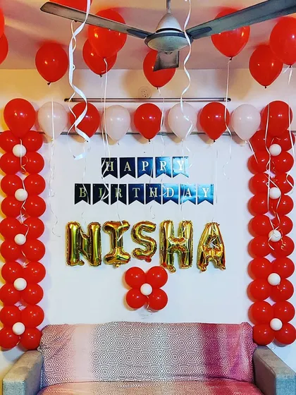 A classic red and white birthday decoration. This setup includes two balloon pillars and 'Happy Birthday' foil letters, creating a bold and cheerful party corner.