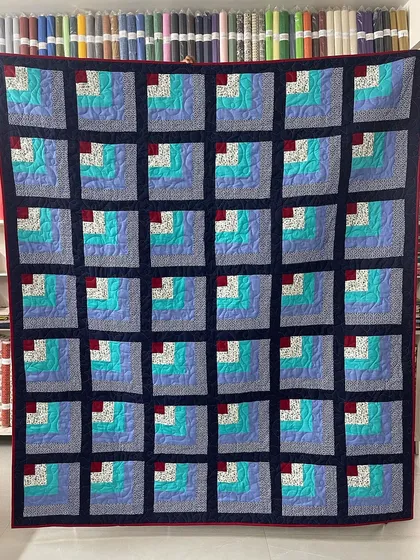A Quarter Log Cabin quilt with a cool color palette of blues and teals.