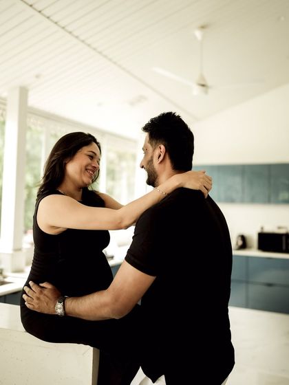 A candid and happy indoor moment. The couple shares a laugh in their kitchen, showing that beautiful moments can be found anywhere.