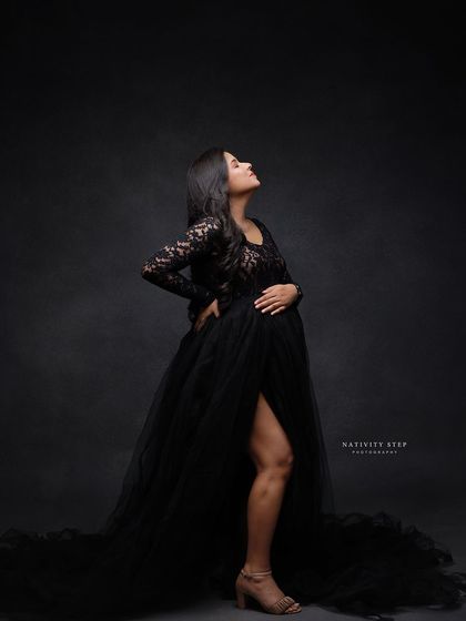 A powerful and elegant pose in a black lace gown. The long, flowing skirt and the mother's confident posture create a stunning silhouette.