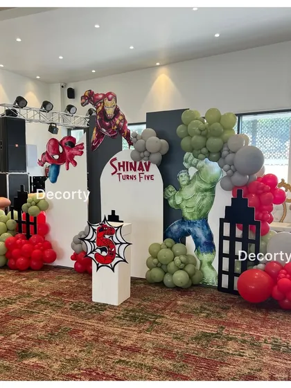 A dynamic superhero backdrop for Shinav's fifth birthday. Life-sized cutouts of Iron Man, Spider-Man, and the Hulk are set against a city skyline.