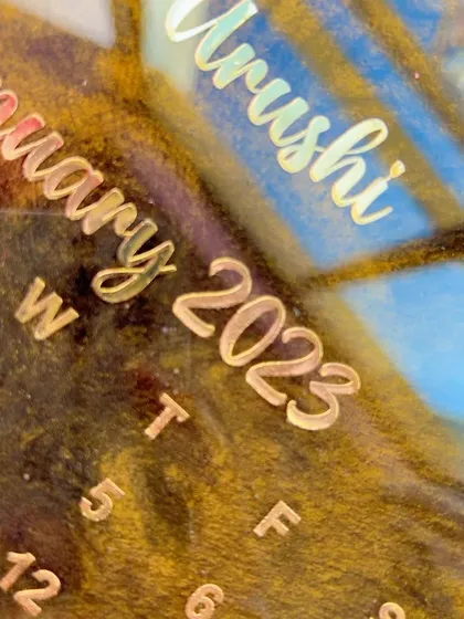 This macro shot highlights the texture and depth of the resin. You can see how the gold text seems to float above the shimmering, dark background of this custom calendar piece.