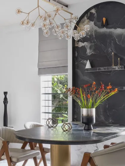 For Dr. Harsha's home, we created a dramatic dining nook with a custom-built table integrated into a monolithic dark tile wall. This space-saving solution becomes a bold statement piece, contrasting beautifully with the home's otherwise light and airy feel.