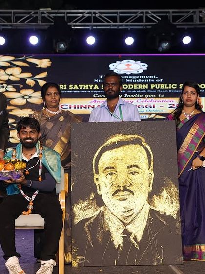 Being felicitated on stage after completing a live glitter portrait at a school event. It's a privilege to share my art with students and faculty.